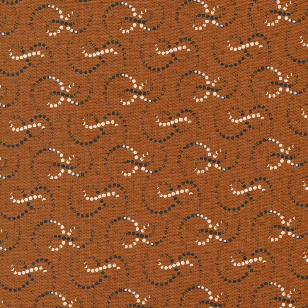 Moda Rustic Gatherings.Swirling white and black dotted lines on a spice colored background.